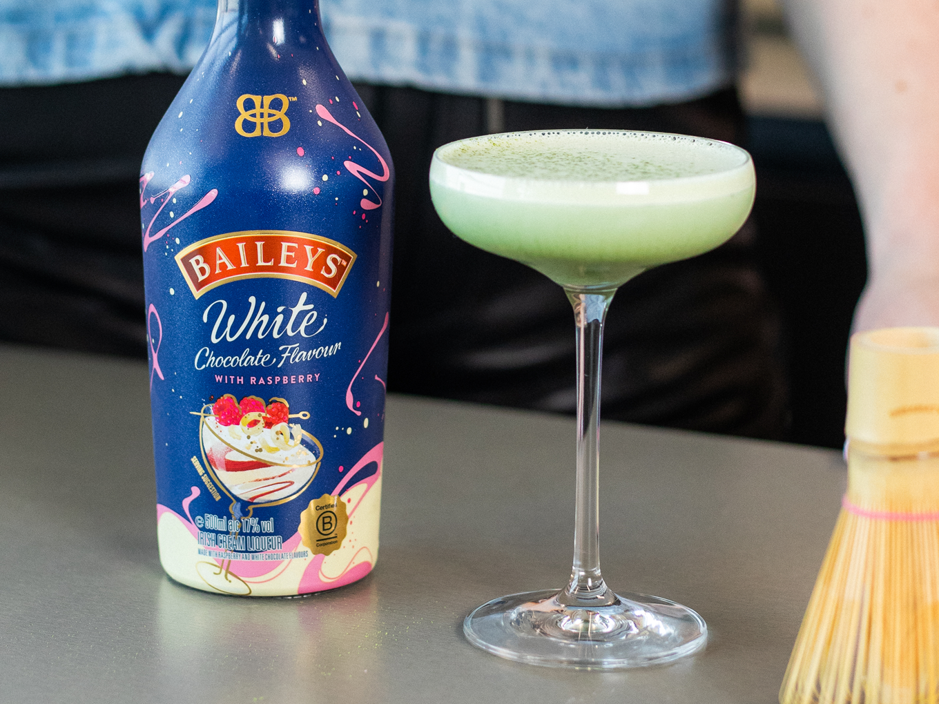 Drinkkilasi, jossa matcha martinia sekä Baileys White Chocolate Flavour Raspberry -pullo