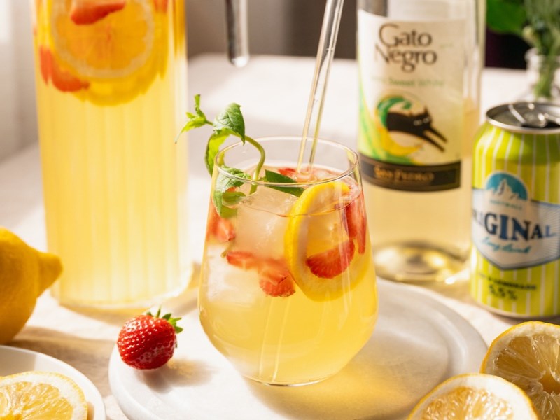 Lasissa valkoviinistä ja lemonade-lonkerosta valmistettua sangriaa. Koristeina pilli, jäitä ja mansikoita.