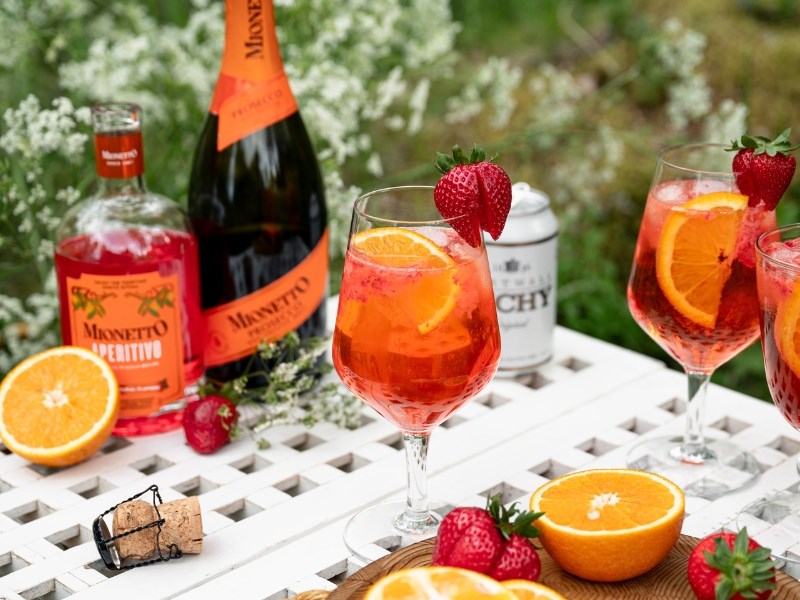 Oranssinpunainen mansikka-aperitivo tarjoiltuna korkeista viinilaseista.